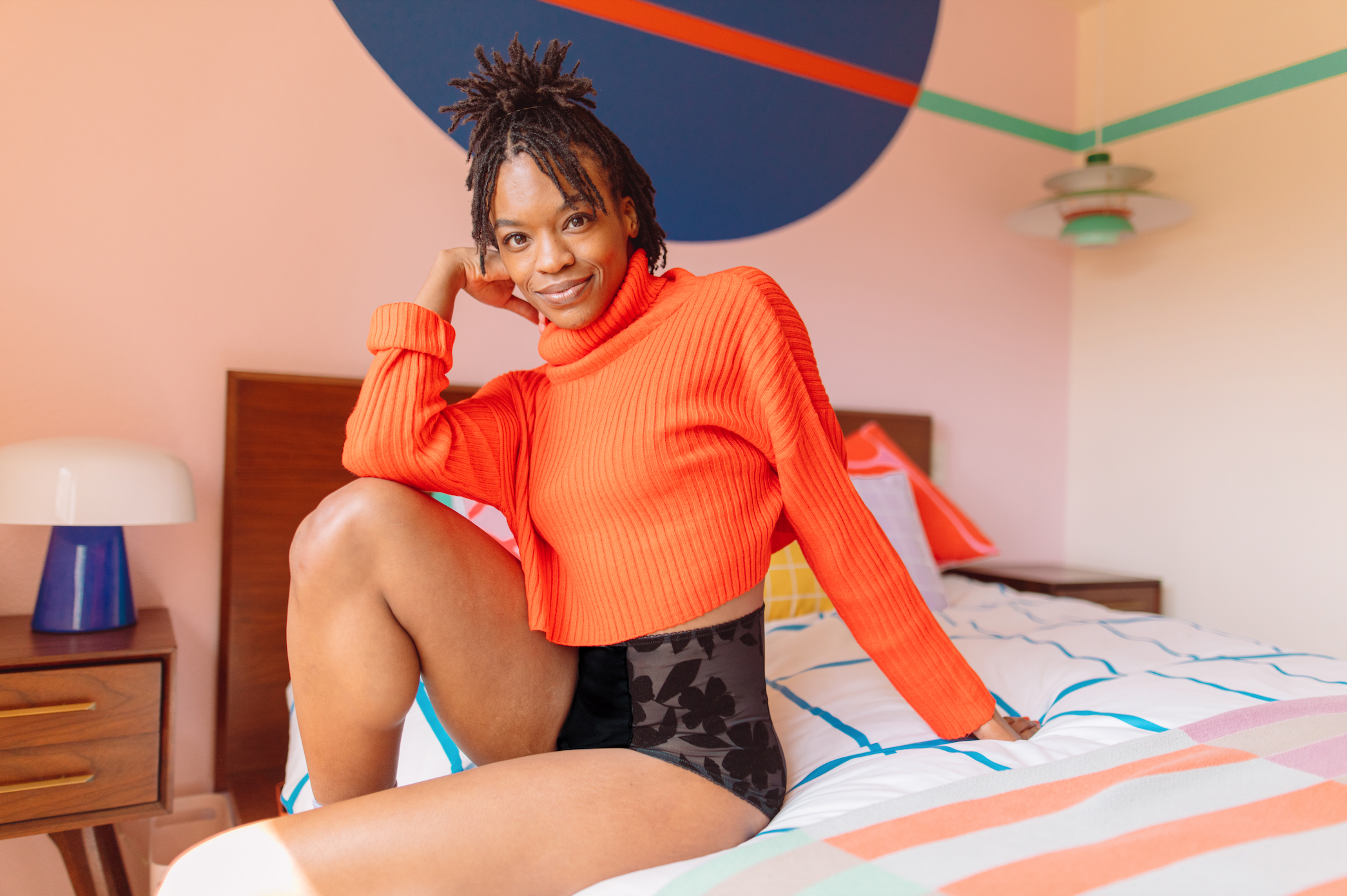 Woman sits on bed wearing Hello Period Undies