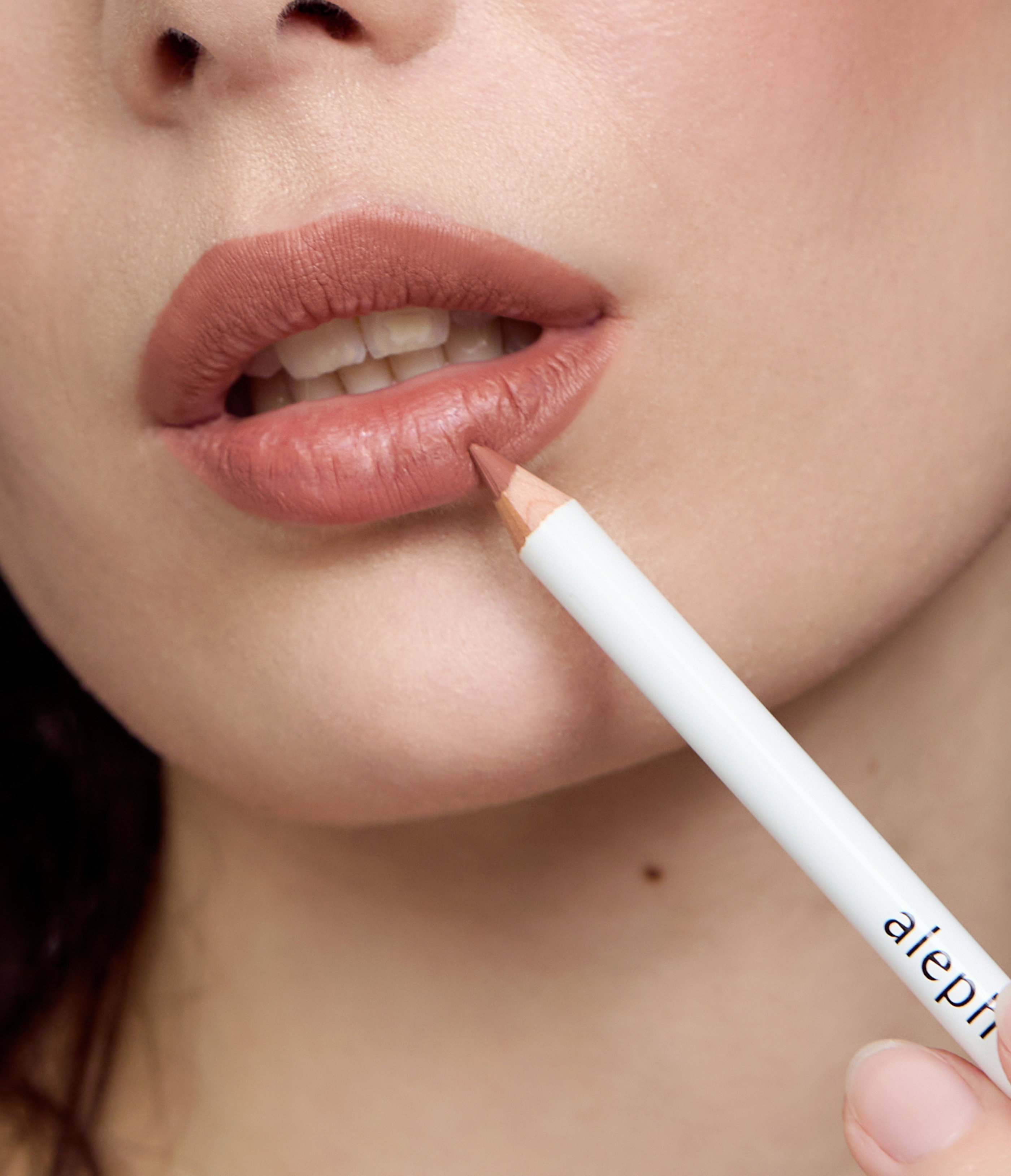 Closeup of model applying Aleph Eye/Lip Multi-liner in Nude