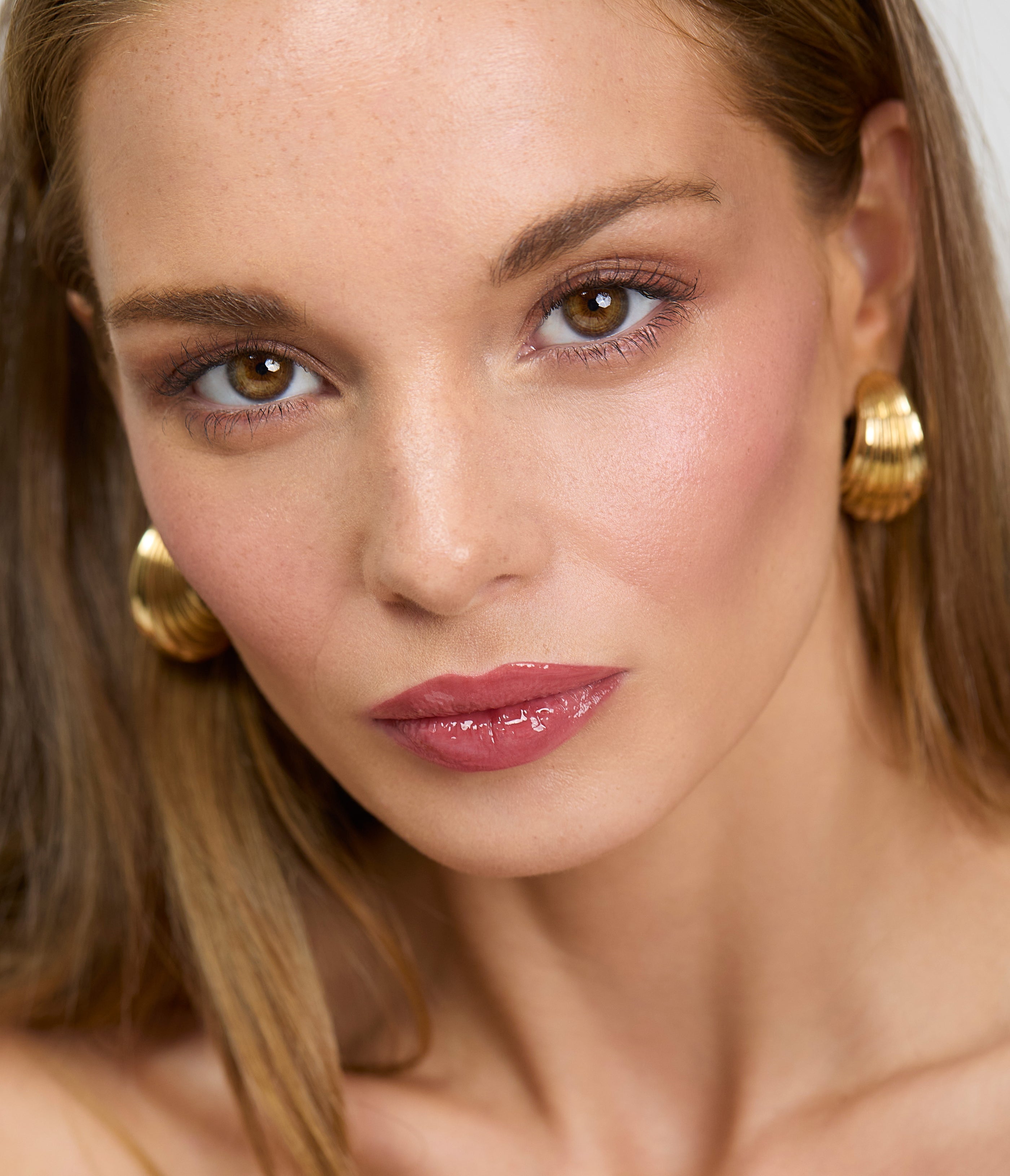 Model wears Aleph Beauty Aura Gloss Ember on the lips