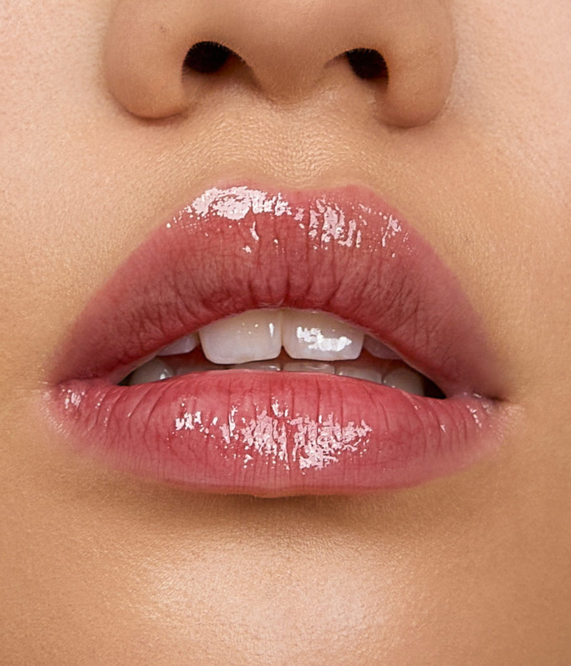 Model wears a light application of Aleph Aura Gloss Ember on the lips