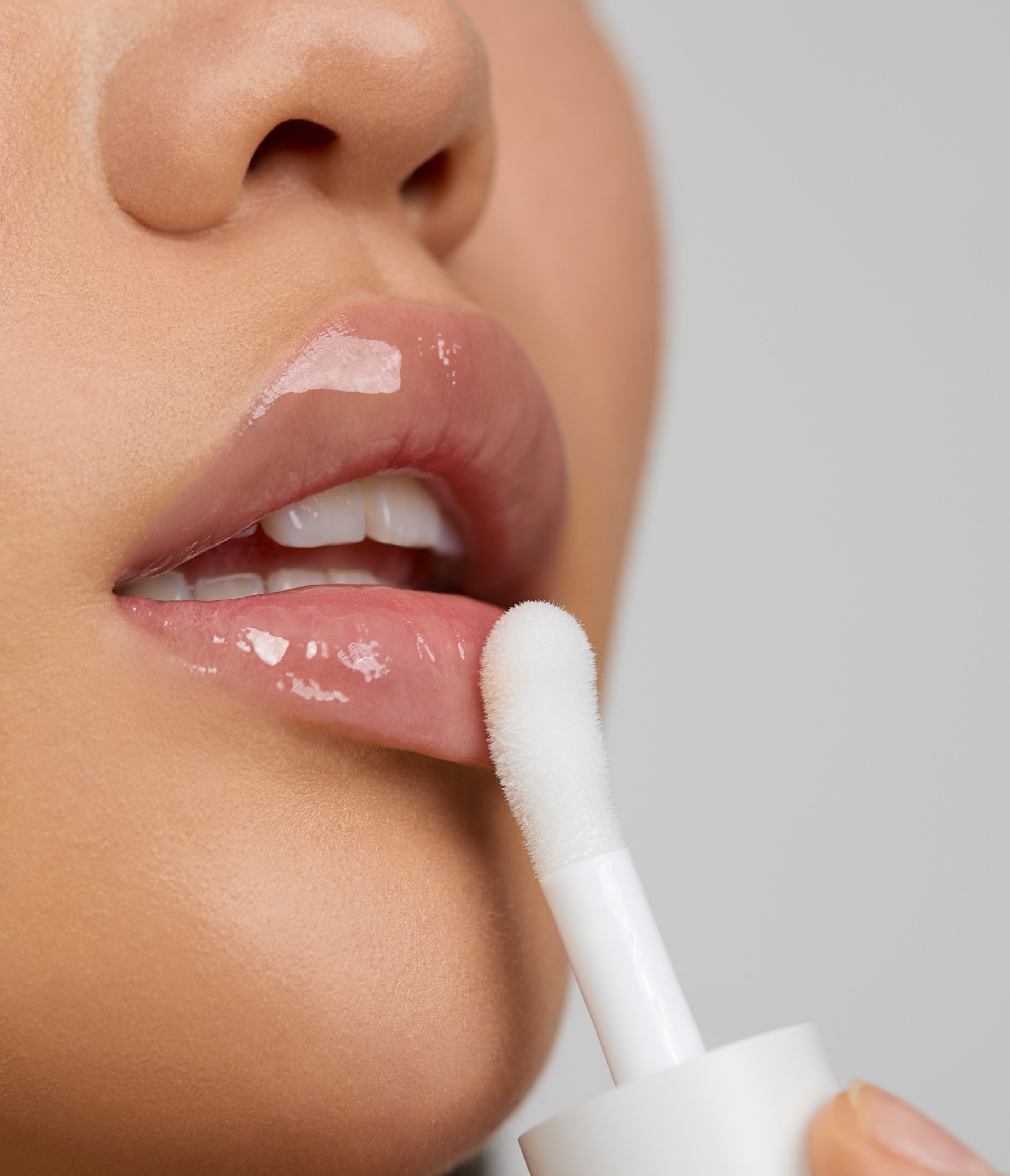 Model applies Aleph Beauty Aura Gloss Lumen with applicator